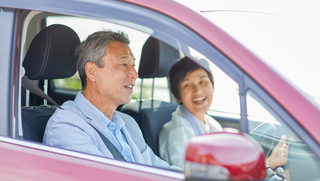 Homem sorridente ao volante de um carro, a mostrar a chave
