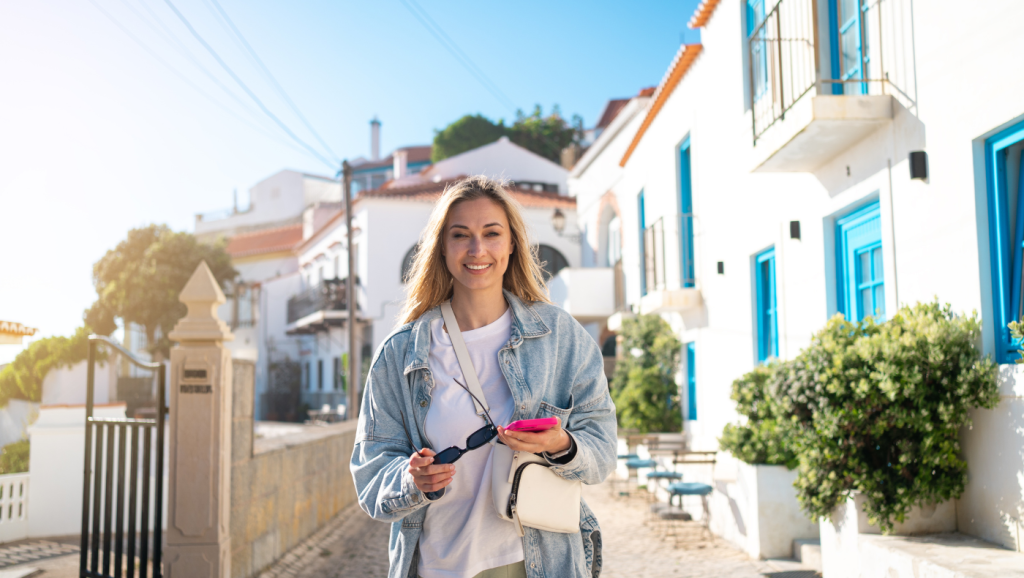 Mulher com documentos na mão numa rua de casas brancas no Algarve